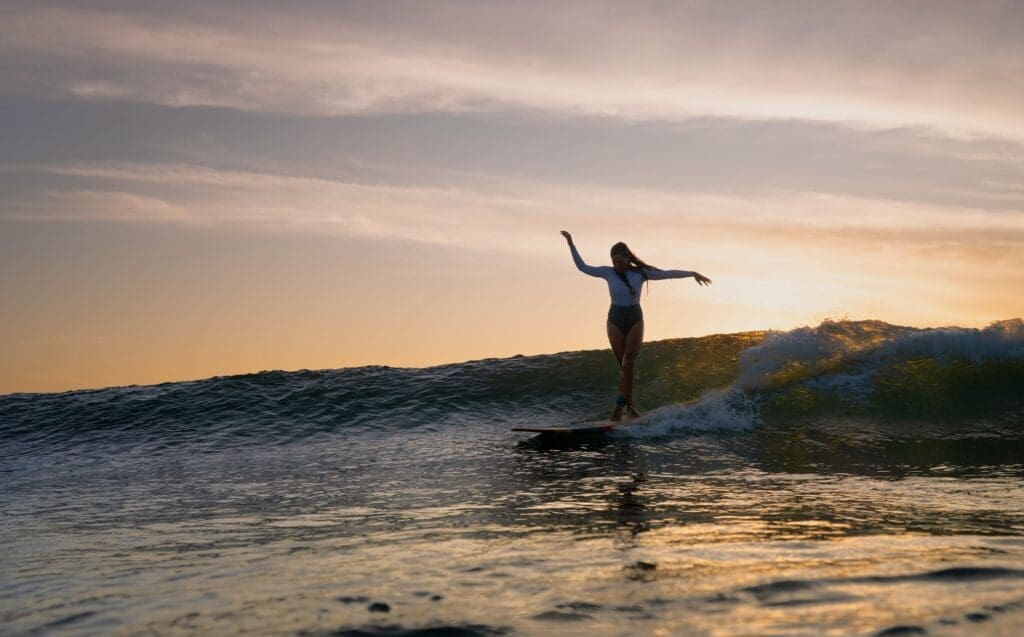 Longboard surfer cross-stepping at sunset, Rote Island