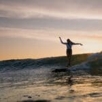 Longboard surfer cross-stepping at sunset, Rote Island